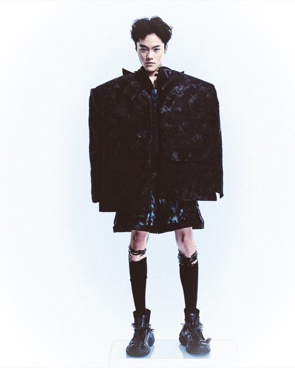Standing full length and closed, the brocade jacket falls in a single column to a jagged hem, dragon embroidery just showing beneath.