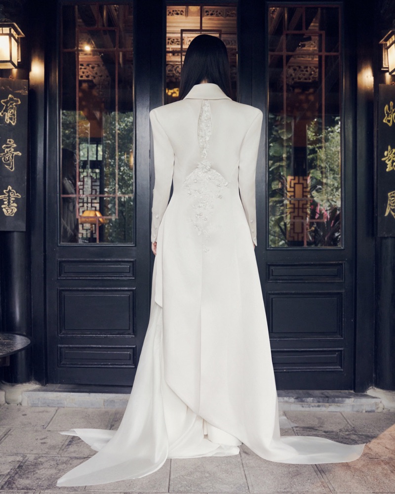 Back view against black lacquer doors showing the floral applique spine and organza train
